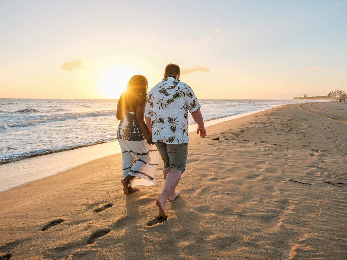 A couple walking the shore at sunset