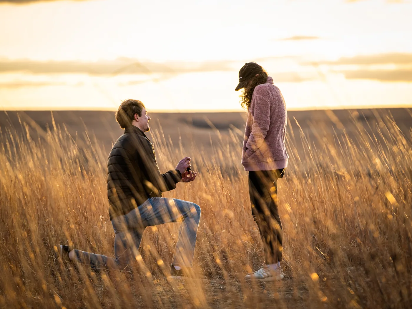Two people in tall Flint Hills grass at sunset